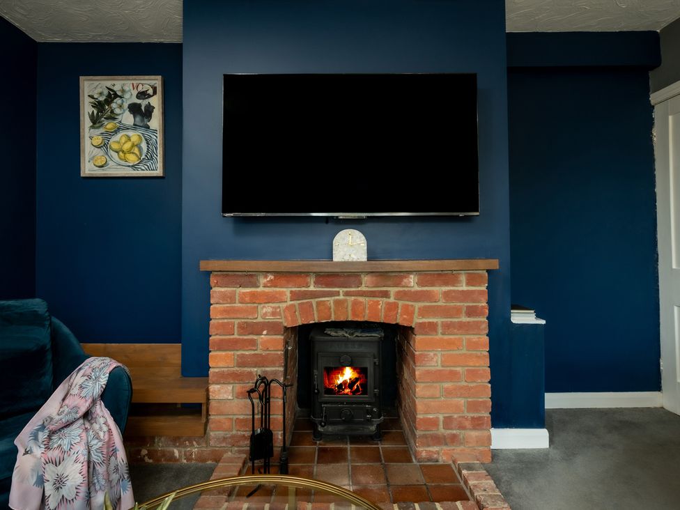 A living room featuring a television above a fireplace at Charming Countryside Cottage in Blandford Forum