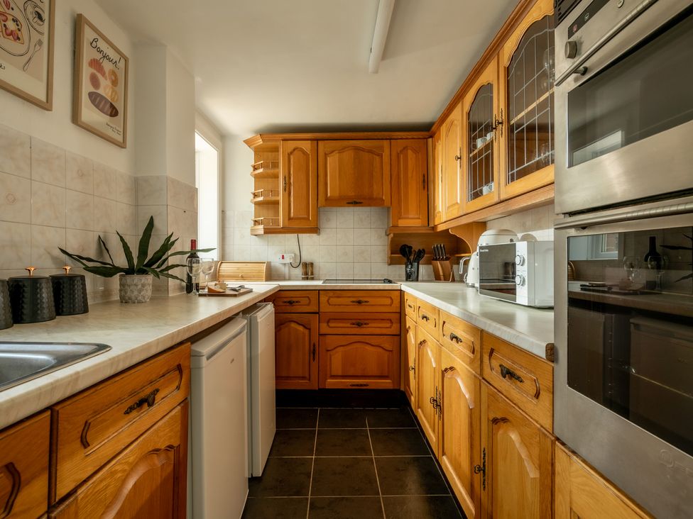 A kitchen with wood cabinets and appliances at Charming Countryside Cottage in Blandford Forum