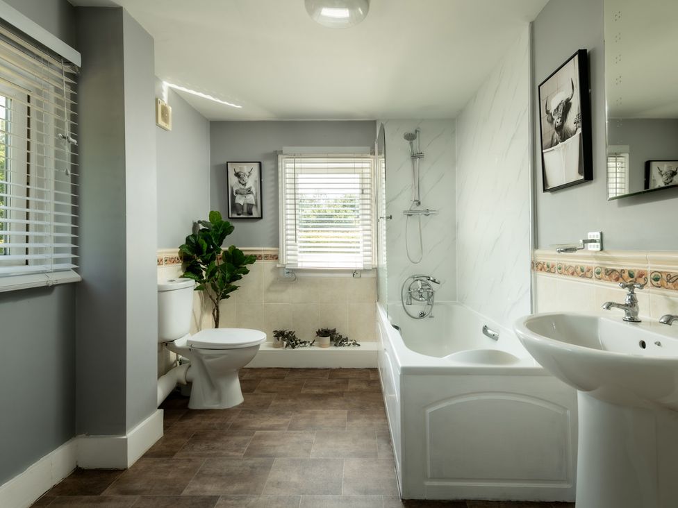 A bathroom with a bath tub, toilet, and sink at Charming Countryside Cottage in Blandford Forum