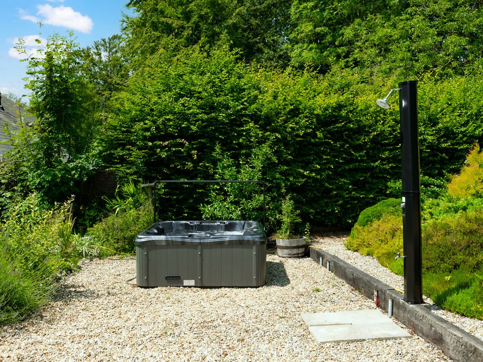 A hot tub and outdoor shower in the garden at Charming Countryside Cottage in Blandford Forum