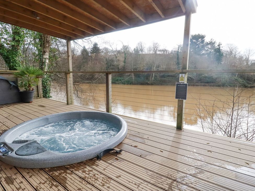 An outdoor area with a hot tub and a view of the river at 1 Water's Edge