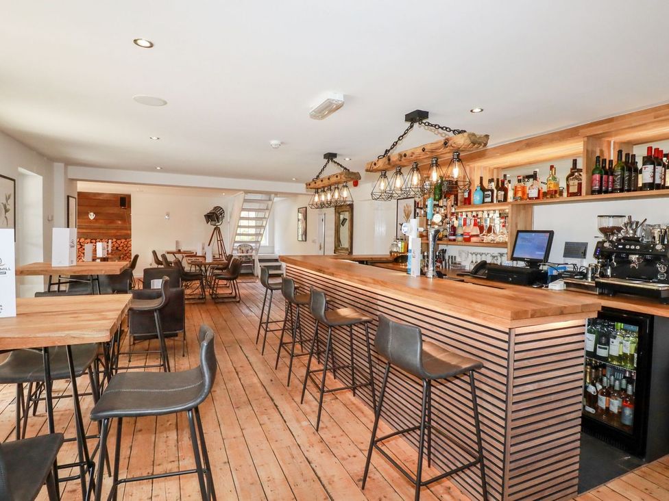 A bar with wooden counter and stools at 1 Water's Edge
