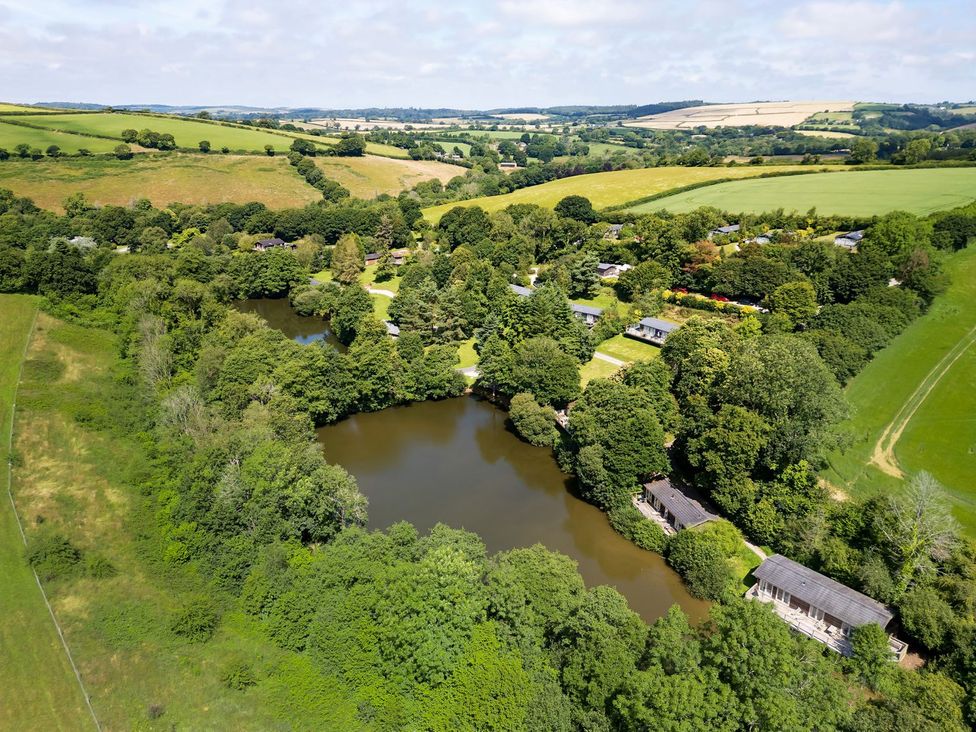 An aerial view of a lake surrounded by trees and cabins at 1 Water's Edge