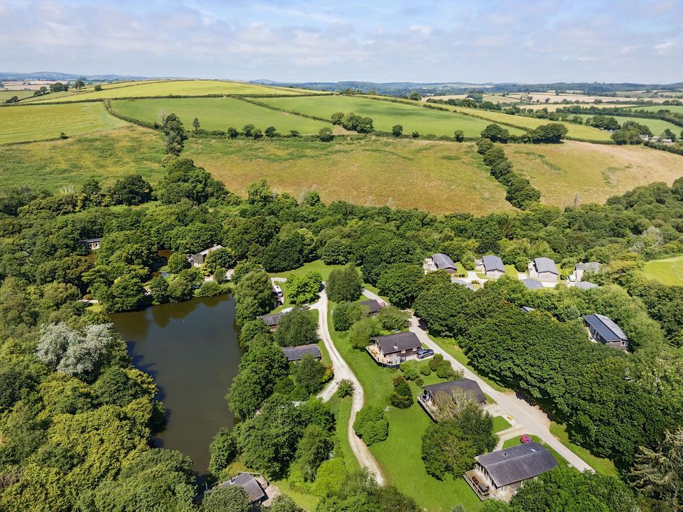 An aerial view of houses around a pond and fields at 1 Water's Edge