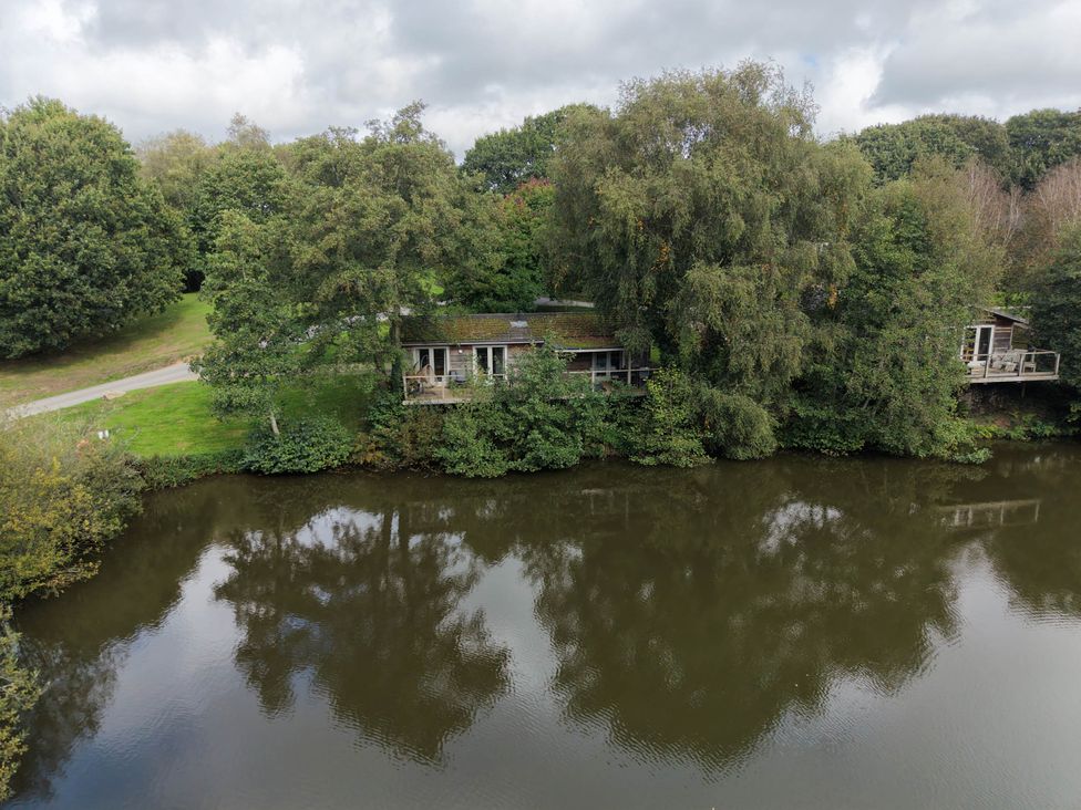 A view of houses by the water surrounded by trees at 1 Water's Edge in Lanreath