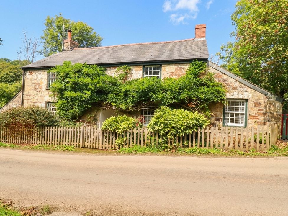 A cottage with a front fence and trees at The Homestead in 