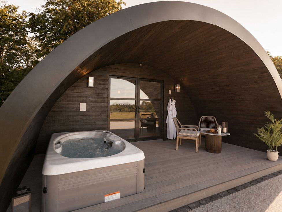 An outdoor area with a hot tub and seating at The Hog Hut in Llanarth