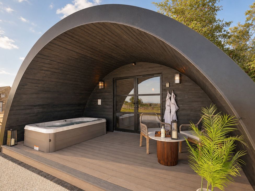 An outdoor area with a hot tub and seating at The Hog Hut in Llanarth