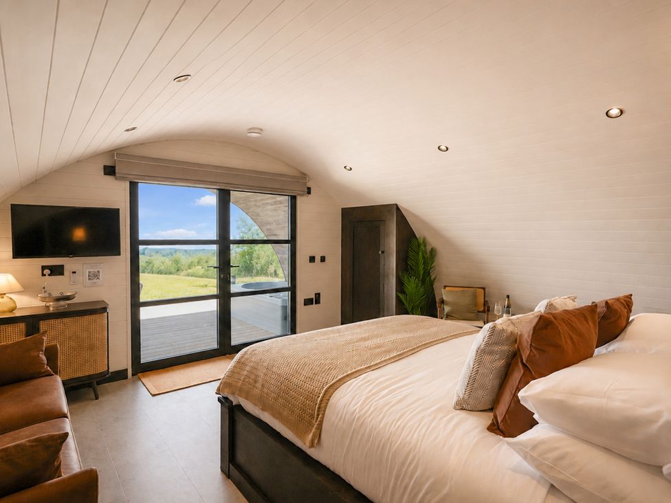 A bedroom with a bed, sofa, and large windows at The Hog Hut in Llanarth
