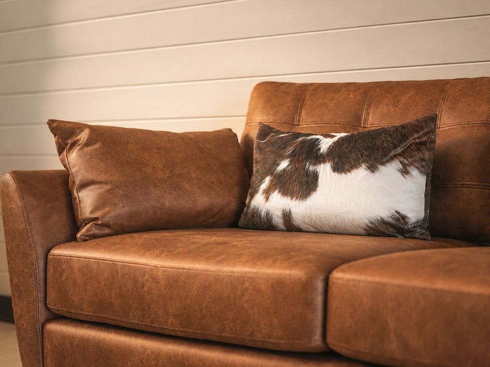 A sofa with a brown cushion and patterned pillow at The Hog Hut in Llanarth