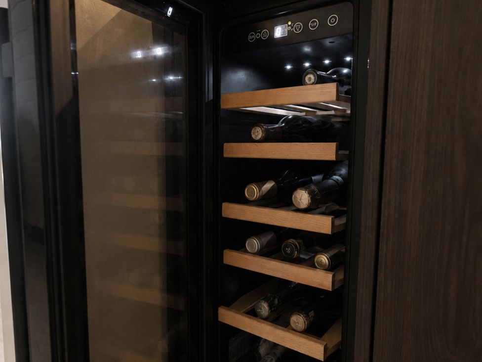 A wine cooler with wooden shelves and bottles at The Hog Hut in Llanarth