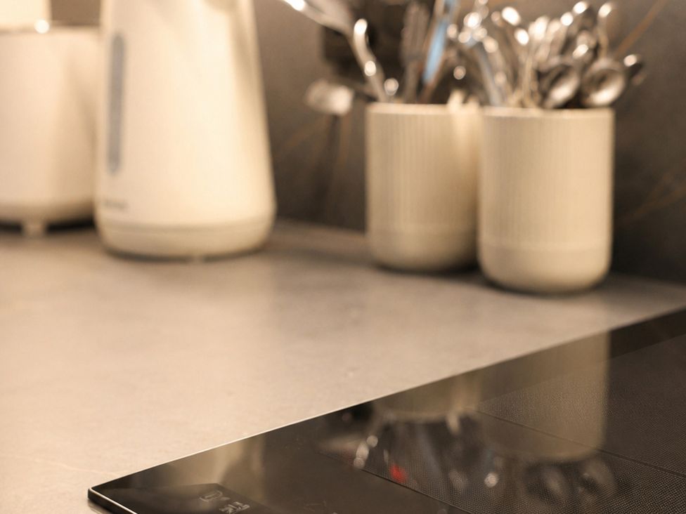 A kitchen with a counter, kettle, and cutlery holder at The Hog Hut in Llanarth