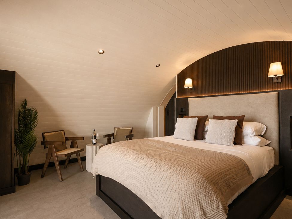 A bedroom with a bed and chairs at The Hog Hut in Llanarth