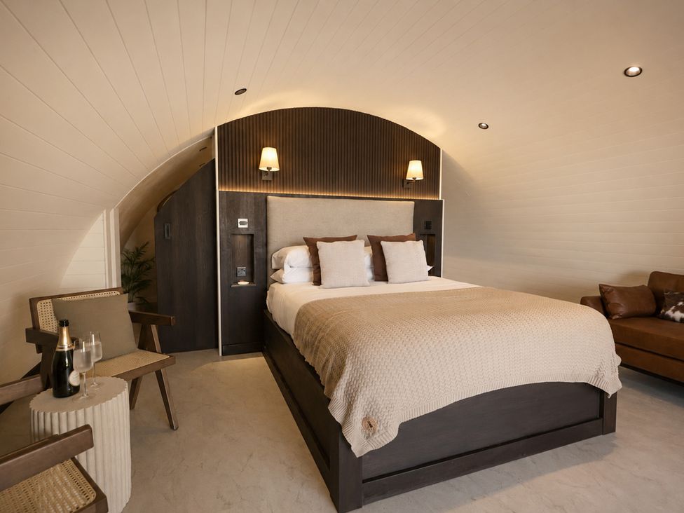 A bedroom with a bed and sofa at The Hog Hut in Llanarth