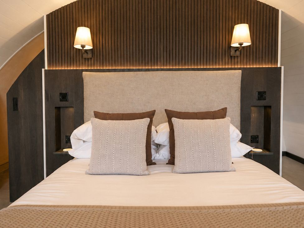 A bed with pillows and bedside lamps at The Hog Hut in Llanarth