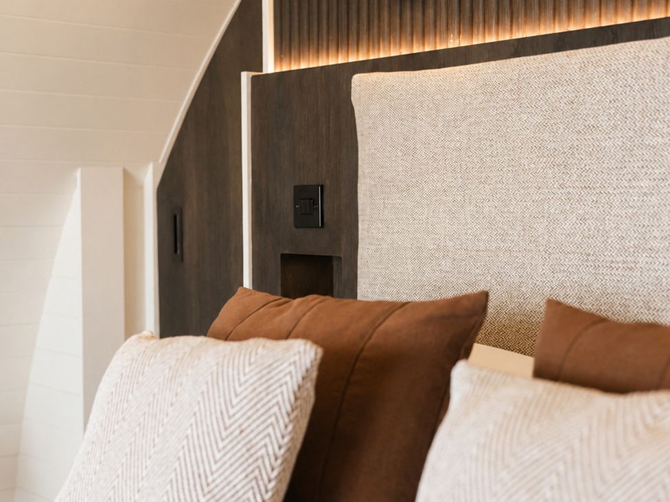 A bed with a headboard and pillows at The Hog Hut in Llanarth