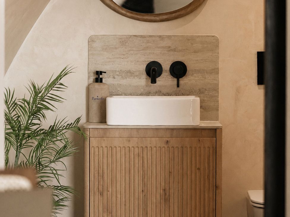 A bathroom featuring a sink, faucet, and mirror at The Hog Hut in Llanarth