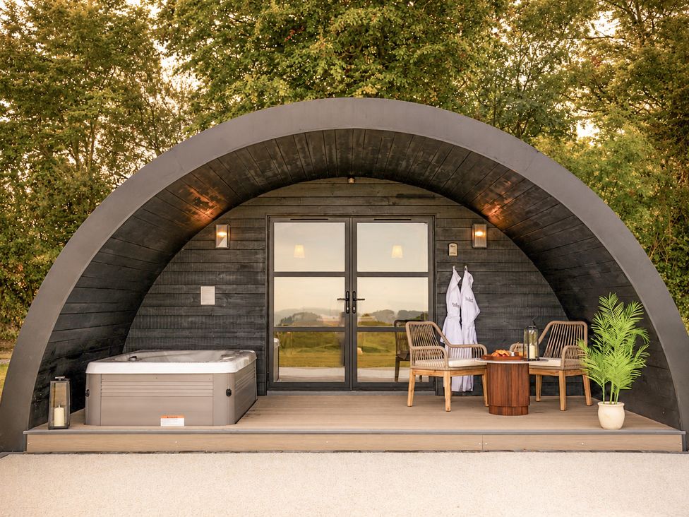 An outdoor area with a hot tub and seating at The Hog Hut in Llanarth