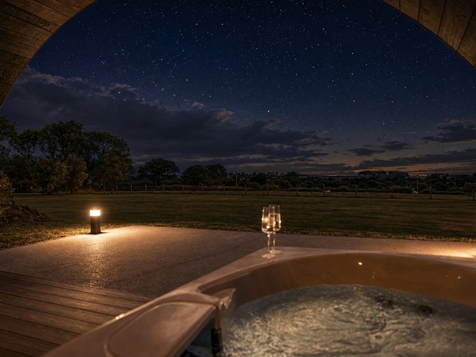 A hot tub with a glass beside it and a view of the night sky at The Hog Hut in Llanarth