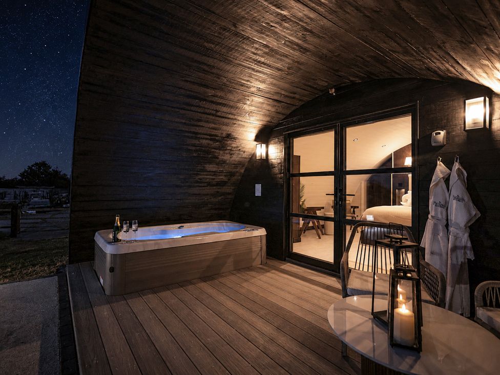 An outdoor area with a hot tub and seating at The Hog Hut in Llanarth
