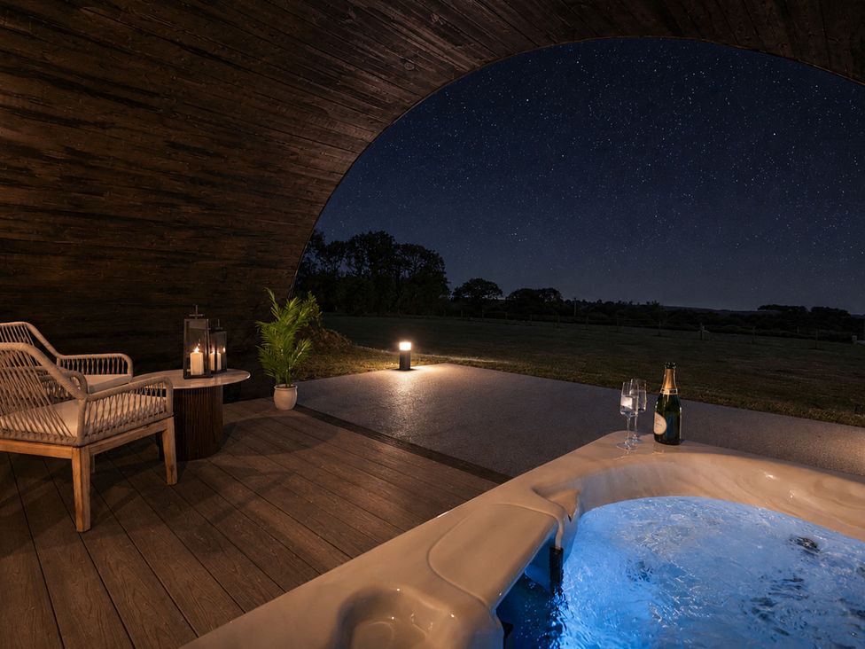 An outdoor area with a hot tub, seating, and a view of the stars at The Hog Hut in Llanarth