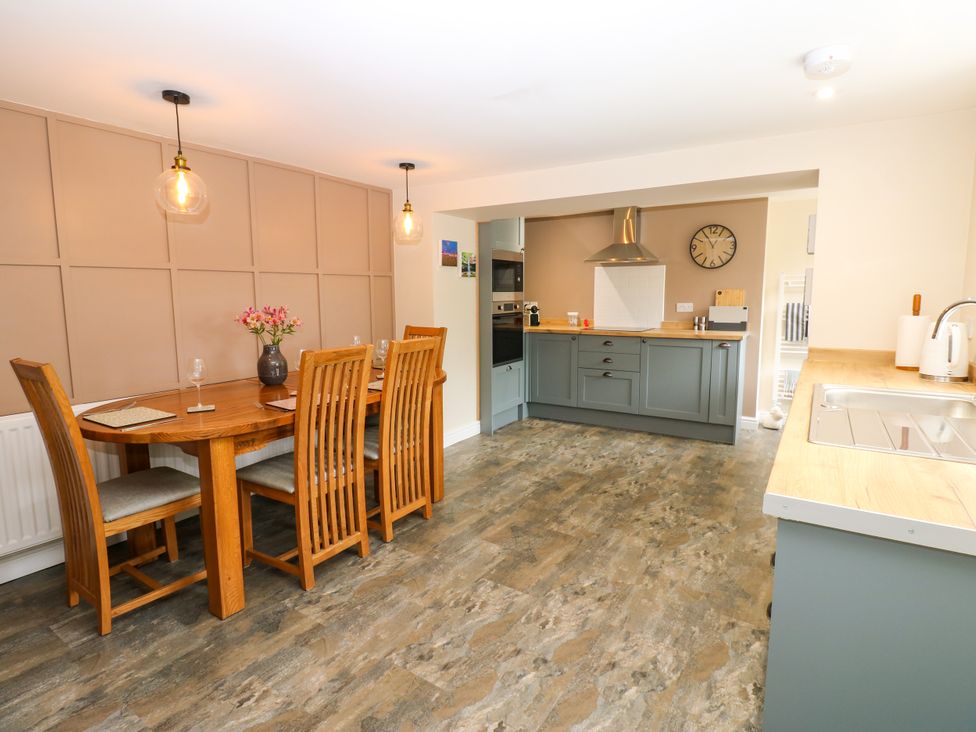 A dining area with a table and kitchen in Woody Bank