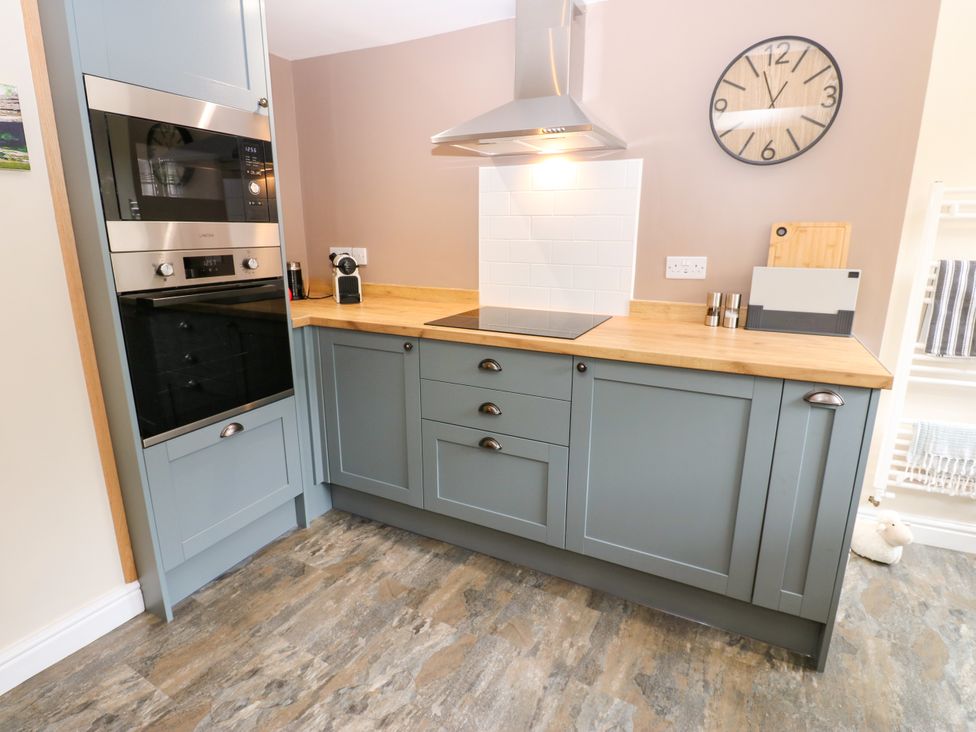 A kitchen with grey units and wooden counter at Woody Bank