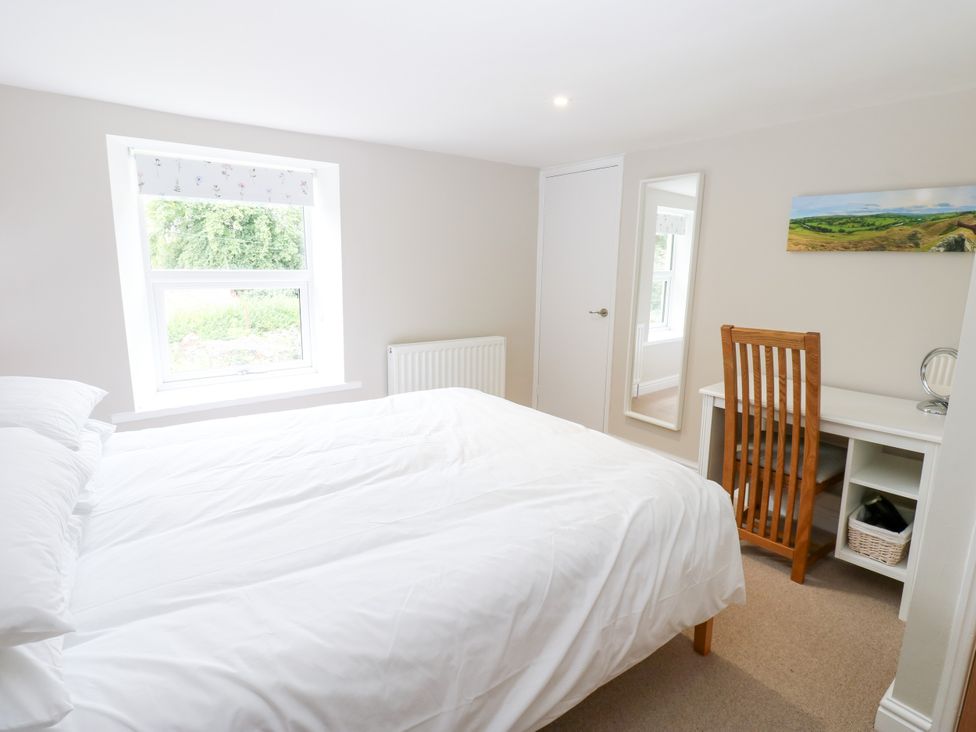 A bedroom featuring a bed, desk, and window at Woody Bank