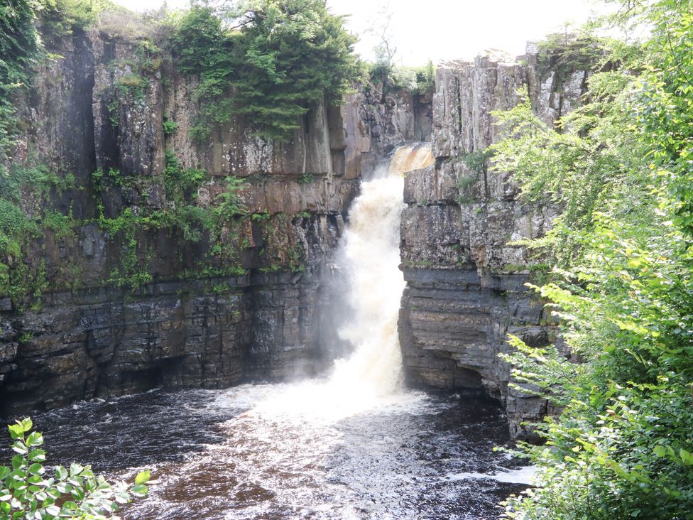 A waterfall cascading over a cliff into a river at Woody Bank in 