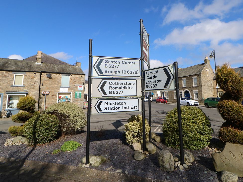 Directional signs at a road junction with buildings and bushes at Woody Bank