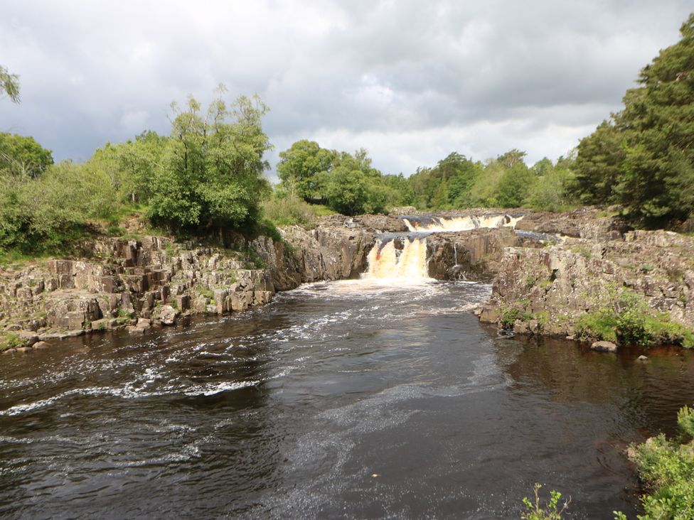 A waterfall cascading over rock formations near a river