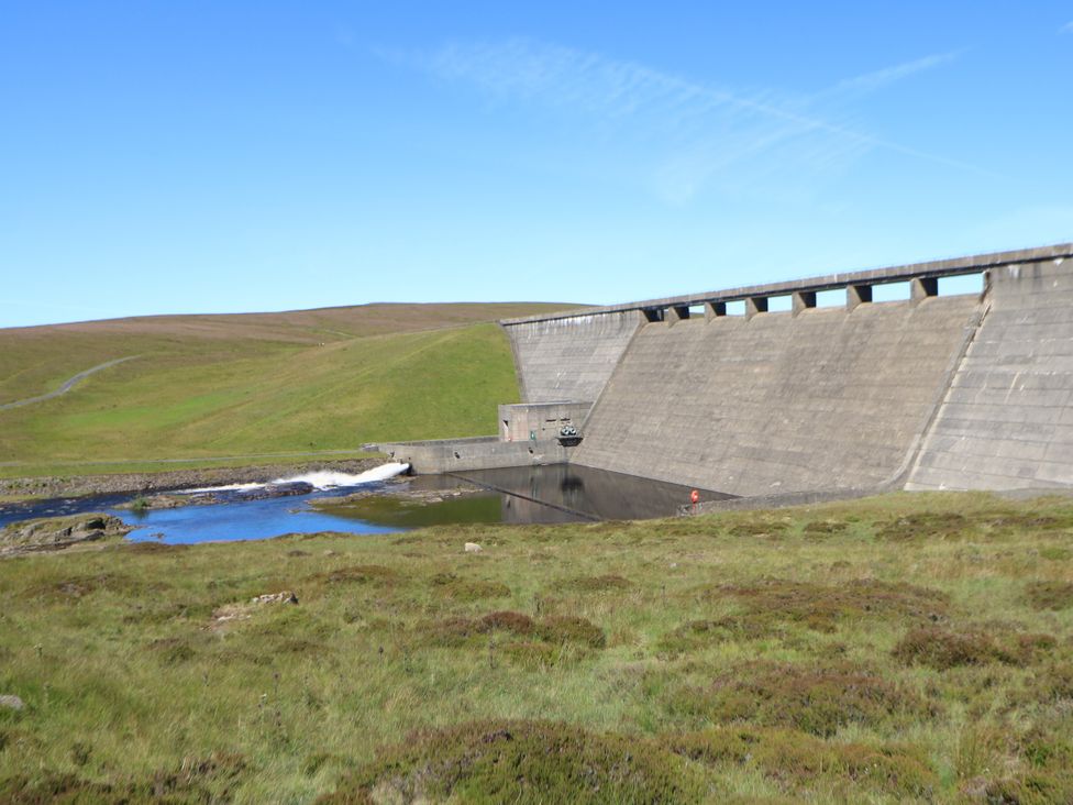 A view of a dam with water outlet and hills at Woody Bank 