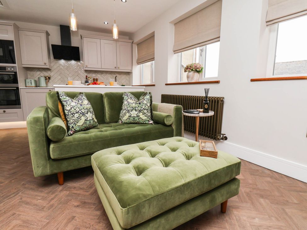 A living room with a green sofa and ottoman at 14 Brunswick Street Whitby