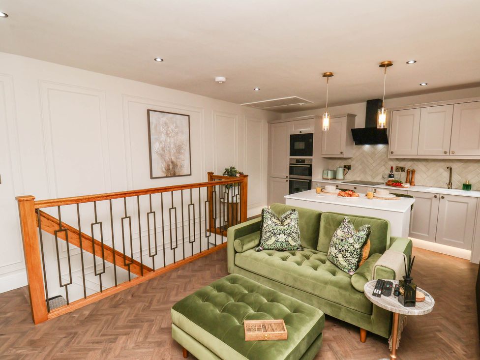 A living room with a green sofa and kitchen in 14 Brunswick Street Whitby