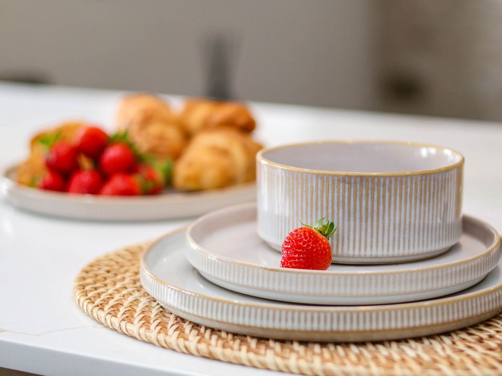 A kitchen table setting with plates, a bowl, strawberries, and croissants at 14 Brunswick Street Whitby