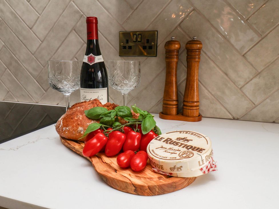 A kitchen countertop with wine, glasses, bread, and cheese at 14 Brunswick Street Whitby