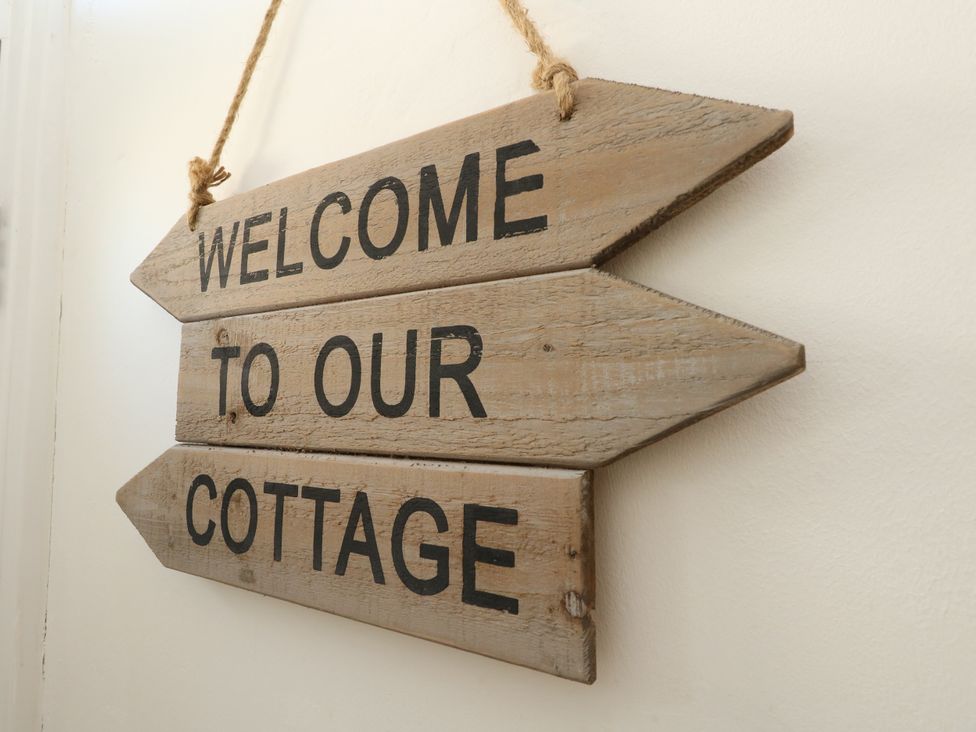 A wooden sign that reads welcome to our cottage at 57 High Street in Portland