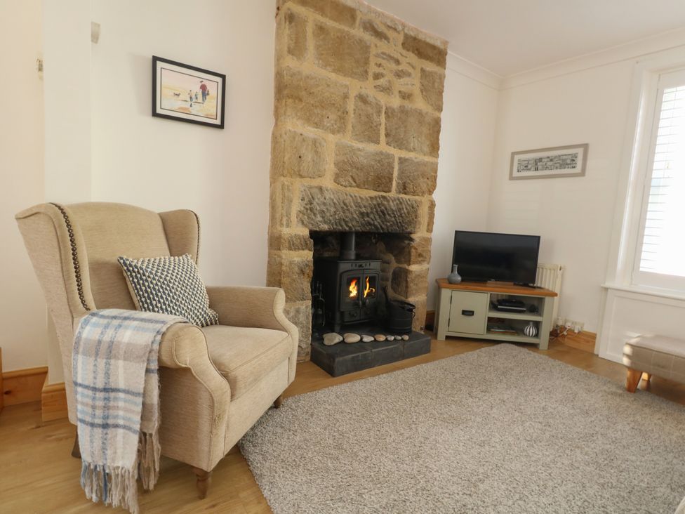 A living room with an armchair and fireplace at 57 High Street