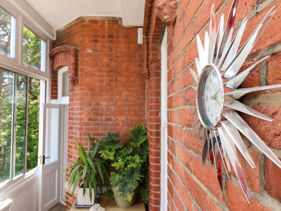 A hallway with a clock on the wall and a plant at The Pines in Bournemouth