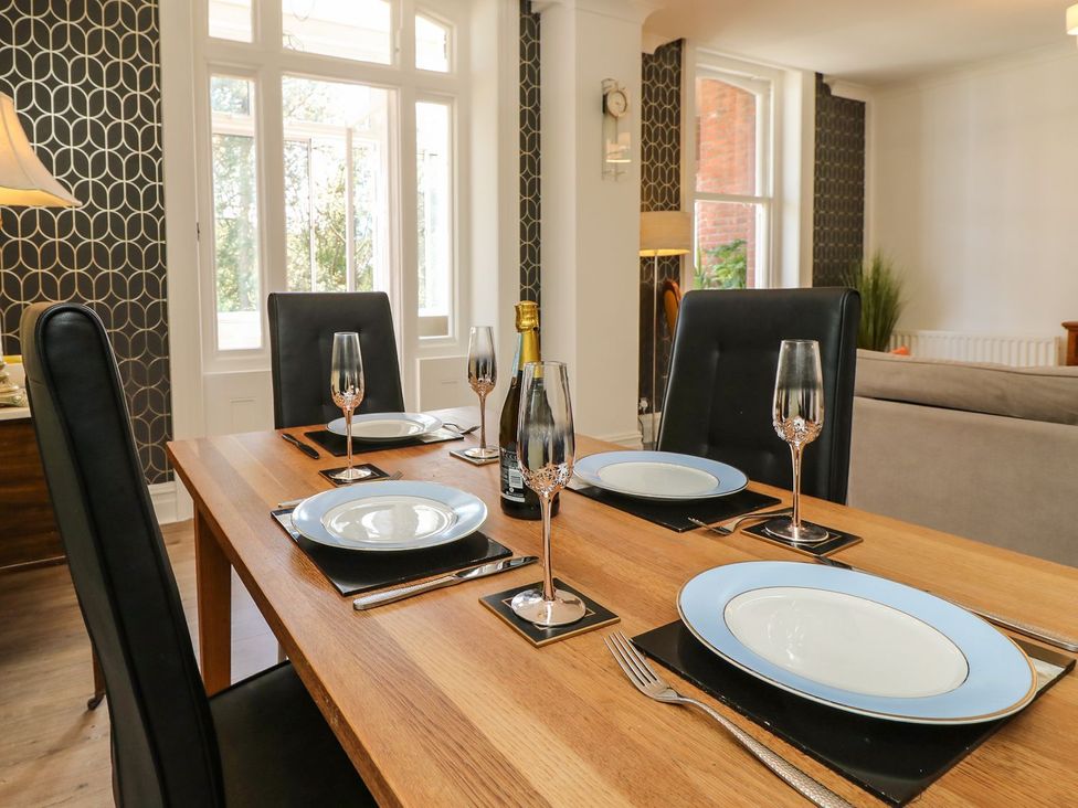 A dining room with a wooden table set for dinner at The Pines Bournemouth
