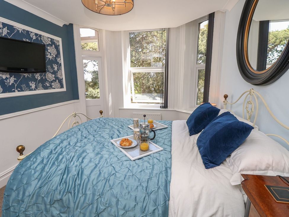 A bedroom with a bed, a television, and a tray with food and drinks at The Pines in Bournemouth