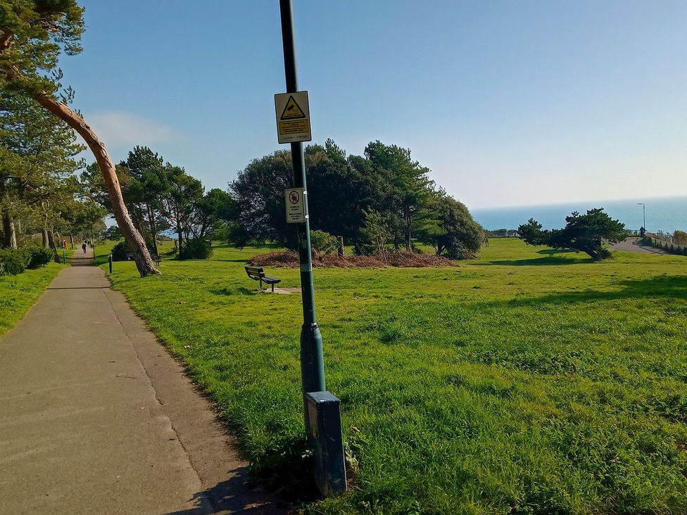 A park with a pathway, trees, and ocean view at The Pines in Bournemouth