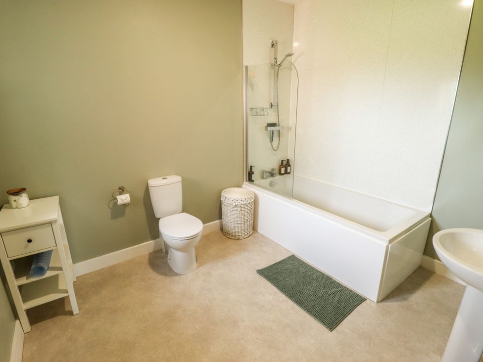 A bathroom with a bathtub, toilet, sink and storage unit at Wold View near Caistor