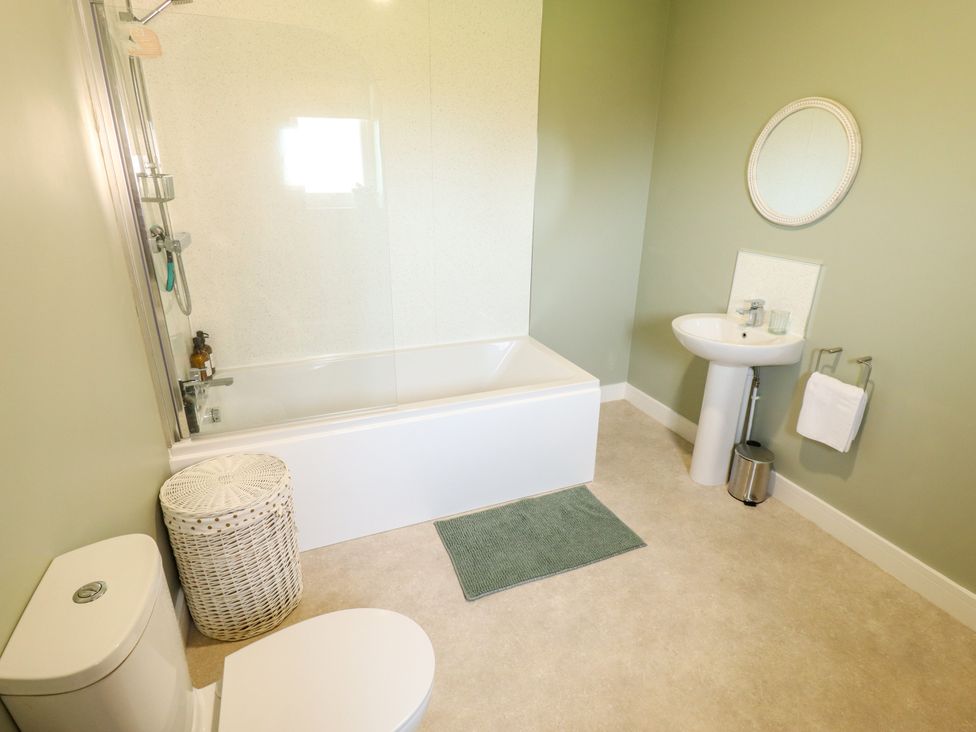 A bathroom with a bathtub, toilet, sink, and mirror at Wold View near Caistor
