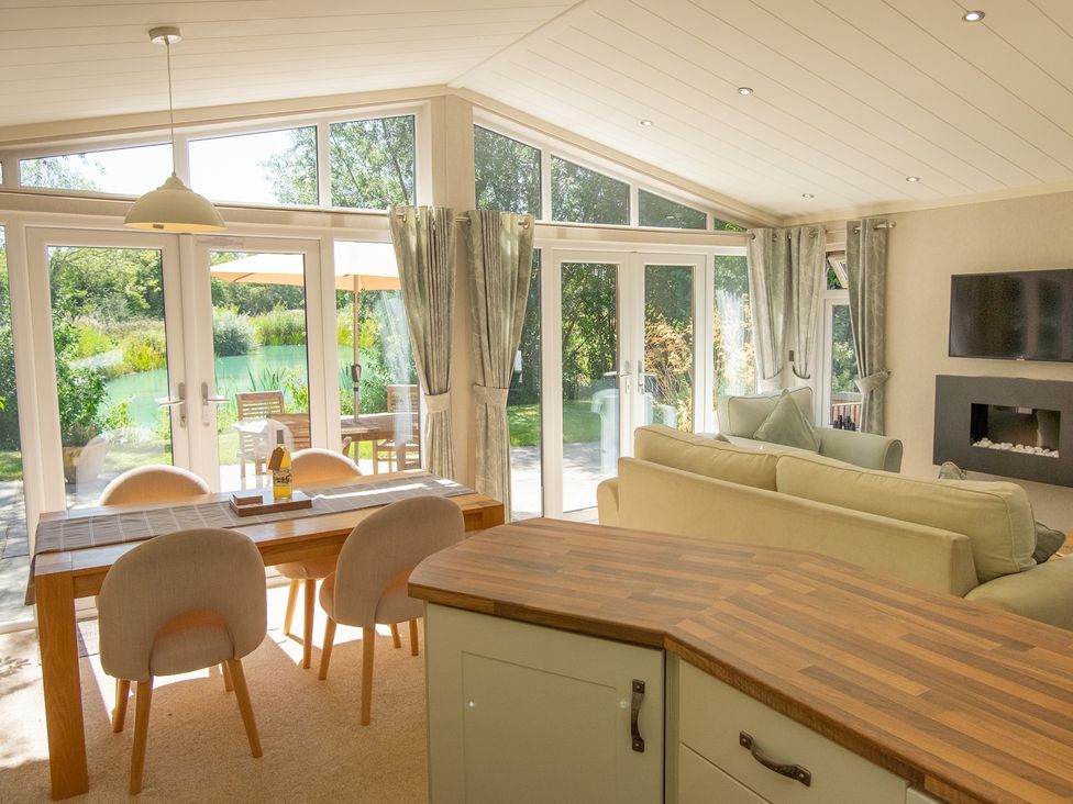 A living room with a dining table and sliding doors at Ash Lodge in Stowmarket