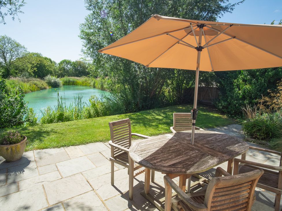 A garden with a table and chairs near a pond at Ash Lodge in Stowmarket