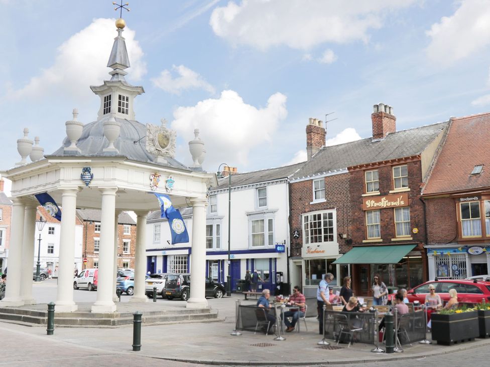An outdoor scene of people dining at tables near a market hall at Millstone Cottage Beverley