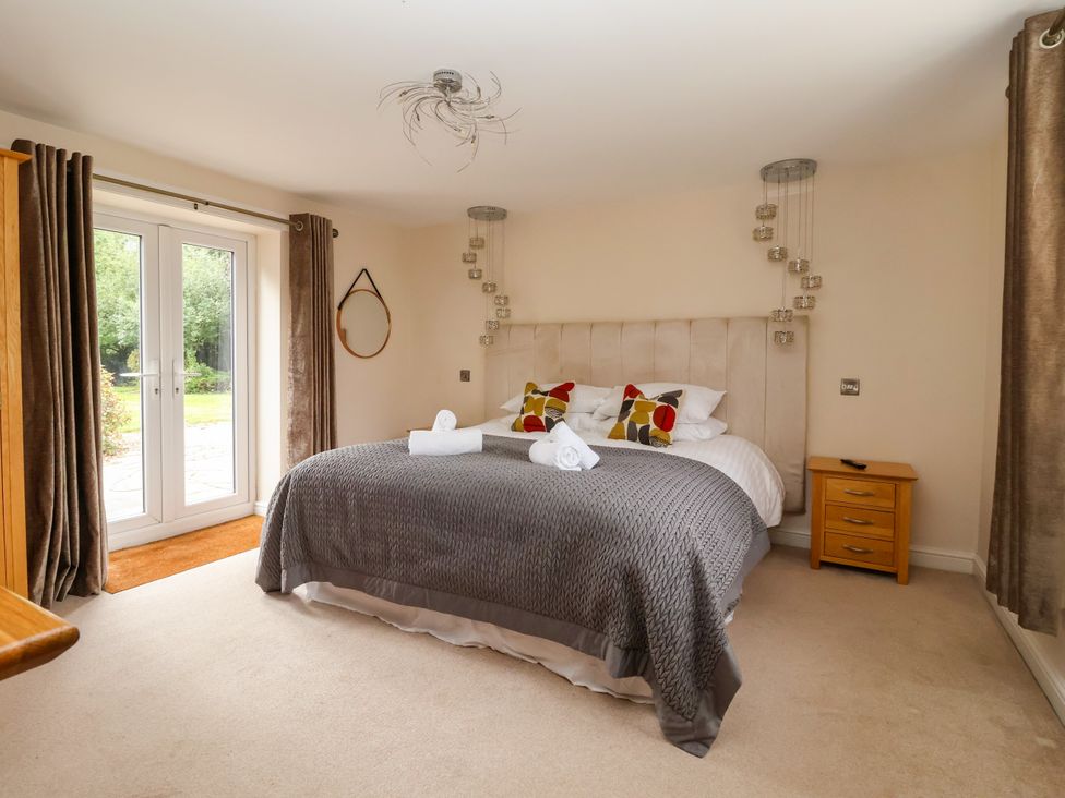 A bedroom with a bed and windows at Millstone Cottage Leven Near Beverley