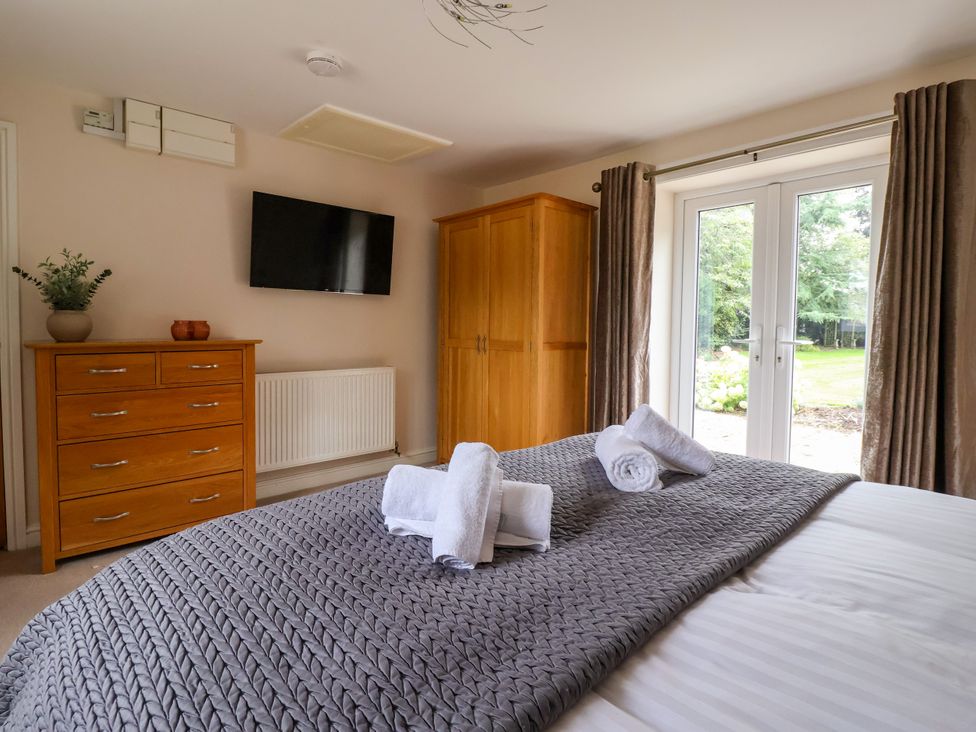 A bedroom with a bed and wardrobe at Millstone Cottage Leven Near Beverley
