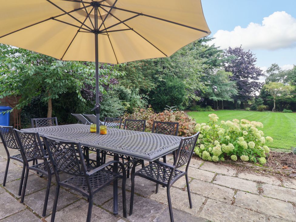 A garden with a table and chairs under an umbrella at Millstone Cottage Leven Near Beverley